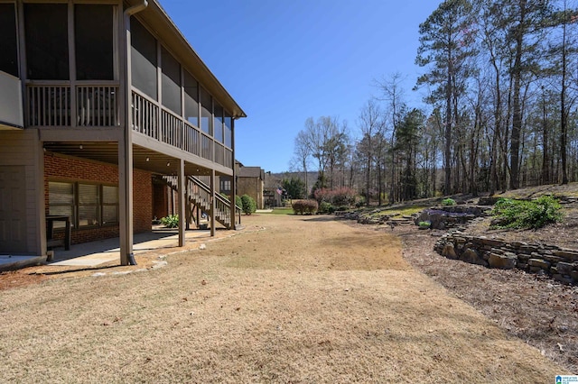 view of yard with a sunroom, stairs, and a patio