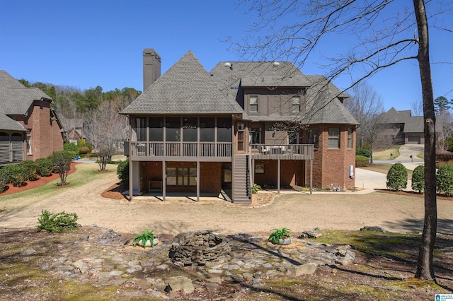 rear view of house with a chimney, a sunroom, a deck, and stairway