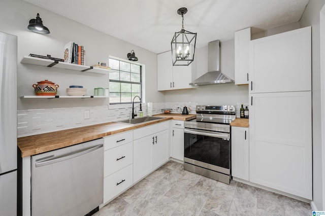 kitchen featuring decorative backsplash, butcher block countertops, appliances with stainless steel finishes, a sink, and wall chimney exhaust hood