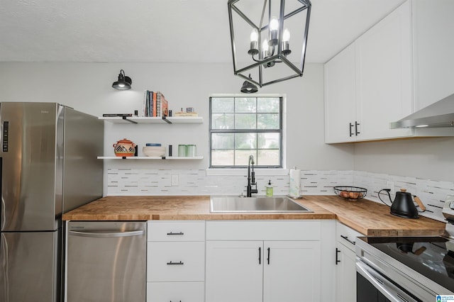 kitchen with tasteful backsplash, a sink, wood counters, stainless steel appliances, and white cabinetry