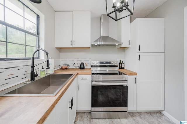kitchen with wall chimney exhaust hood, a sink, electric stove, wood counters, and white cabinetry