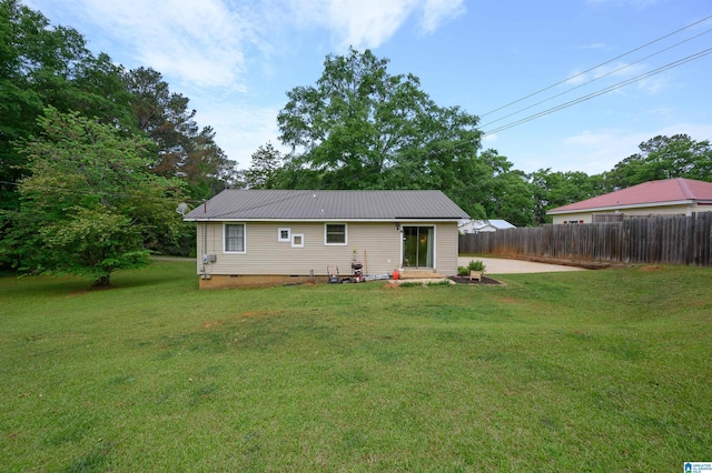 back of house featuring a lawn, fence, crawl space, and metal roof