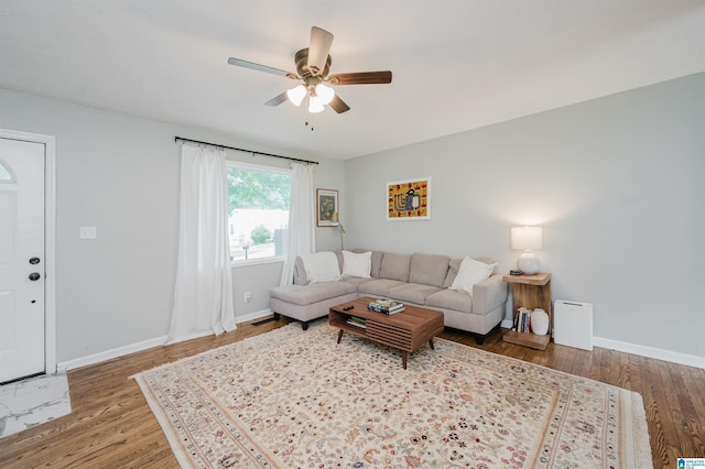 living area featuring baseboards, ceiling fan, and wood finished floors