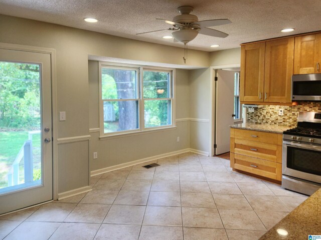 574 Turtle Creek Dr, Hoover, AL 35226 - kitchen with stainless steel appliances, ceiling fan, tasteful backsplash, light stone countertops, and brown cabinetry