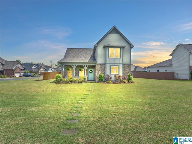 view of front of house featuring fence, a front lawn, and stone siding