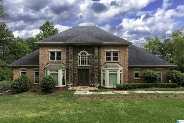 view of front of home with french doors, a shingled roof, a front lawn, and brick siding