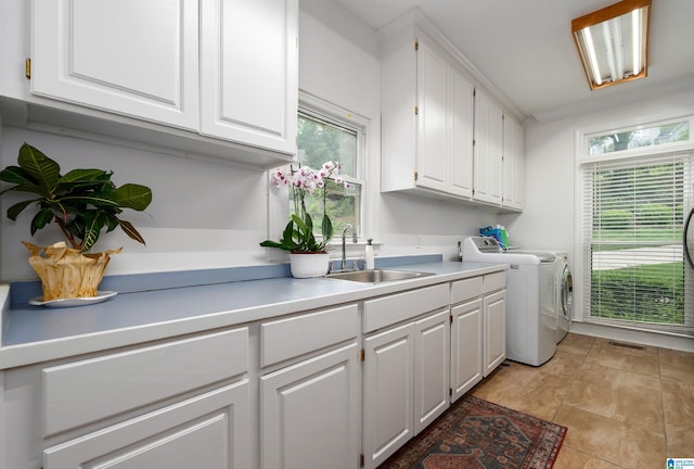 laundry area featuring cabinet space, washing machine and dryer, a sink, and a healthy amount of sunlight