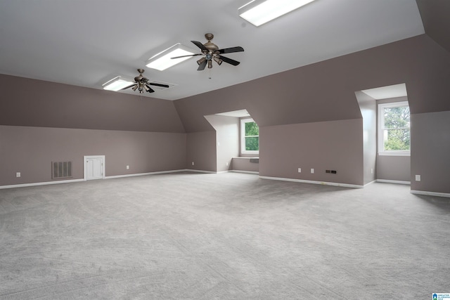 additional living space with baseboards, a wealth of natural light, vaulted ceiling, and visible vents
