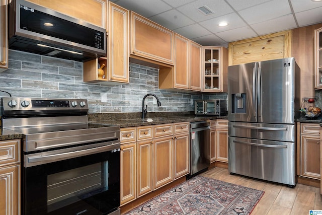 kitchen featuring glass insert cabinets, backsplash, visible vents, light wood-style floors, and stainless steel appliances