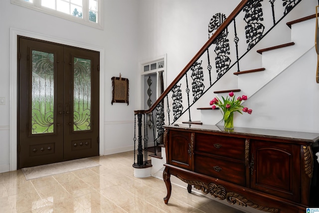 foyer with french doors, baseboards, light tile patterned floors, a towering ceiling, and stairway