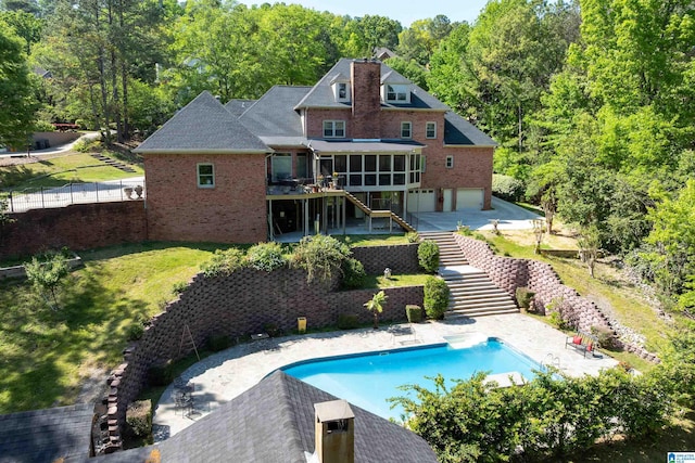 back of property with stairs, brick siding, a garage, a sunroom, and a fenced backyard