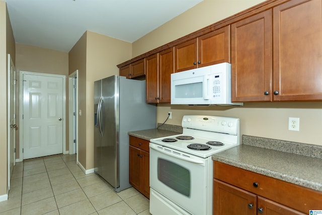 1127 Avalon Dr, Moody, AL 35004 - kitchen with light tile patterned floors, brown cabinets, white appliances, and baseboards