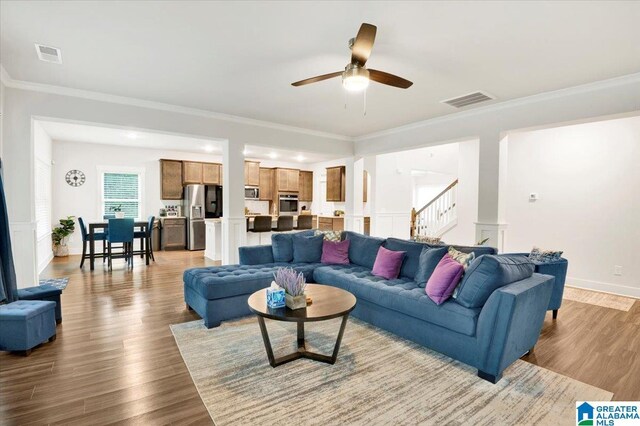 living room featuring visible vents, wood finished floors, ceiling fan, and stairway