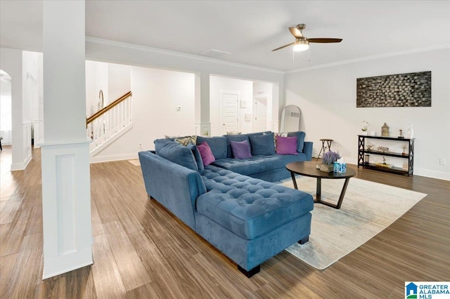 living room with stairway, ceiling fan, baseboards, ornamental molding, and wood finished floors