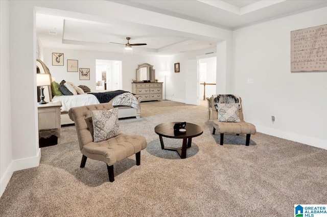 carpeted living area featuring a raised ceiling, a ceiling fan, and baseboards