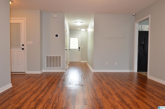 spare room featuring visible vents, baseboards, and dark wood-type flooring