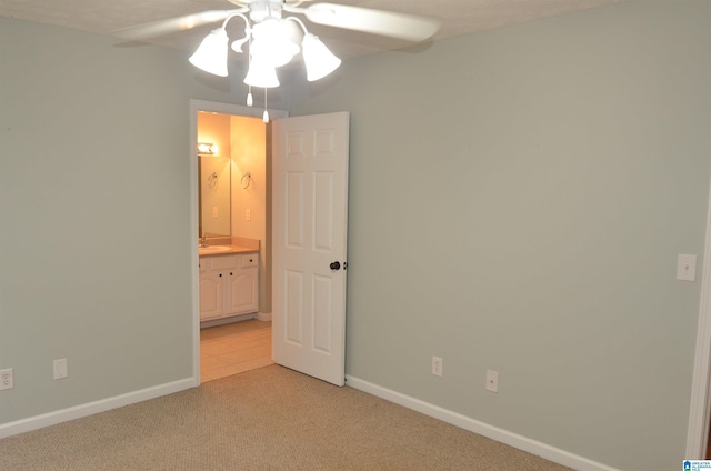 empty room featuring a sink, ceiling fan, light colored carpet, and baseboards