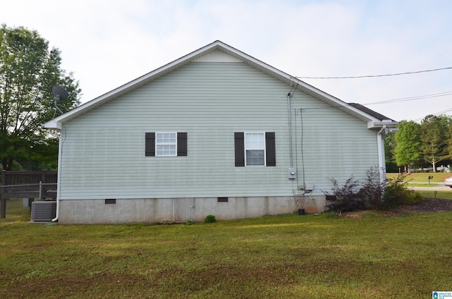 view of side of home with a yard, central air condition unit, and crawl space