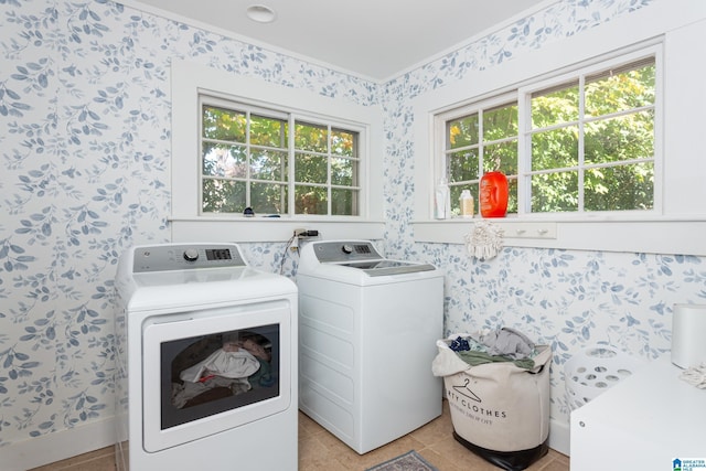 clothes washing area featuring washing machine and dryer, wallpapered walls, laundry area, and a healthy amount of sunlight