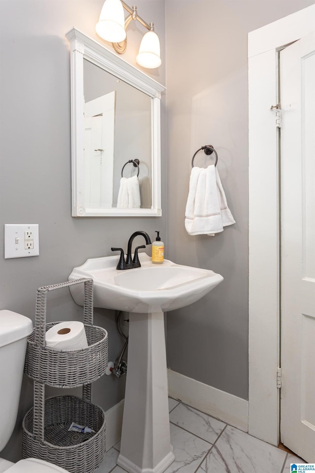 half bathroom featuring baseboards, toilet, and marble finish floor