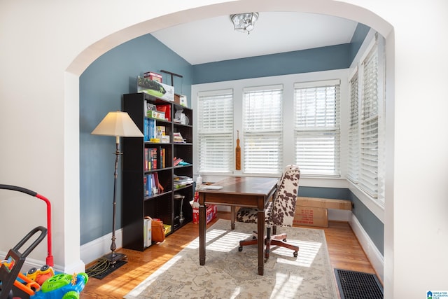 office area featuring baseboards, visible vents, arched walkways, and wood finished floors