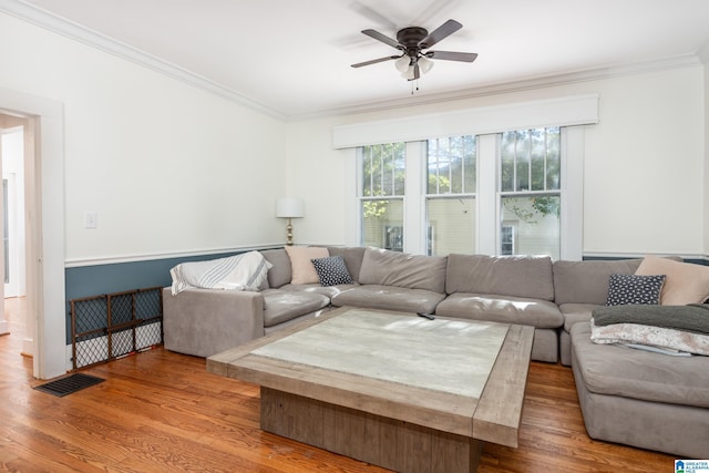 living area with wood finished floors, ceiling fan, crown molding, and visible vents