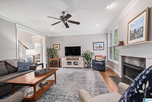 living room with light wood-style floors, a high end fireplace, ceiling fan, and ornamental molding