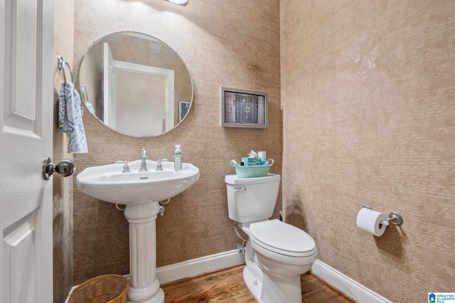 half bathroom with toilet, baseboards, and wood finished floors
