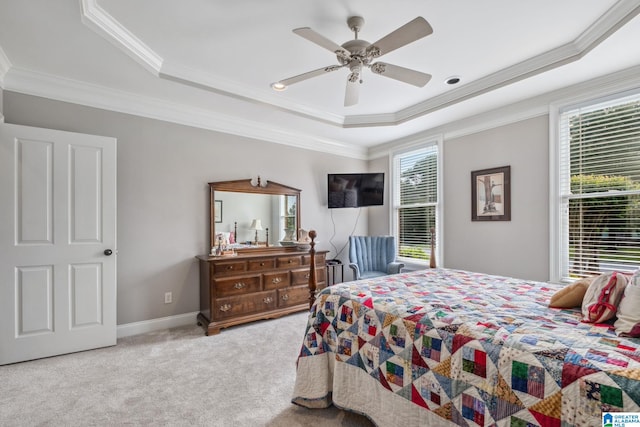 carpeted bedroom with a raised ceiling, ornamental molding, baseboards, and a ceiling fan