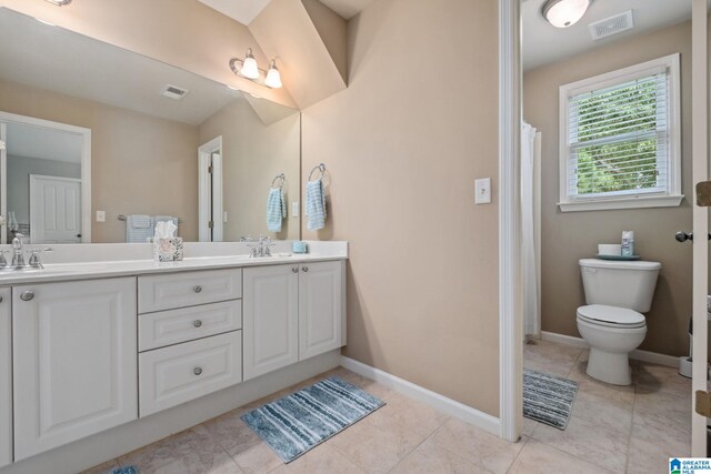 bathroom with double vanity, toilet, visible vents, and a sink