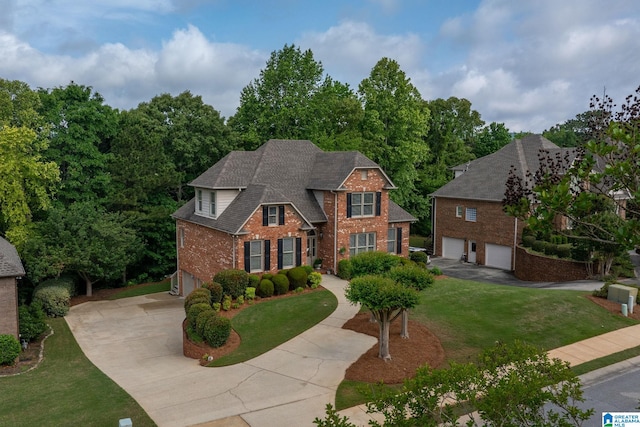 view of front of house with a garage, concrete driveway, a front yard, and brick siding