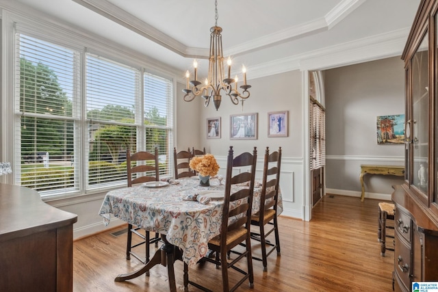 dining area featuring crown molding, an inviting chandelier, plenty of natural light, and light wood-style floors