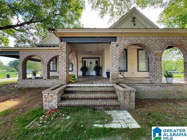 back of property with covered porch and brick siding