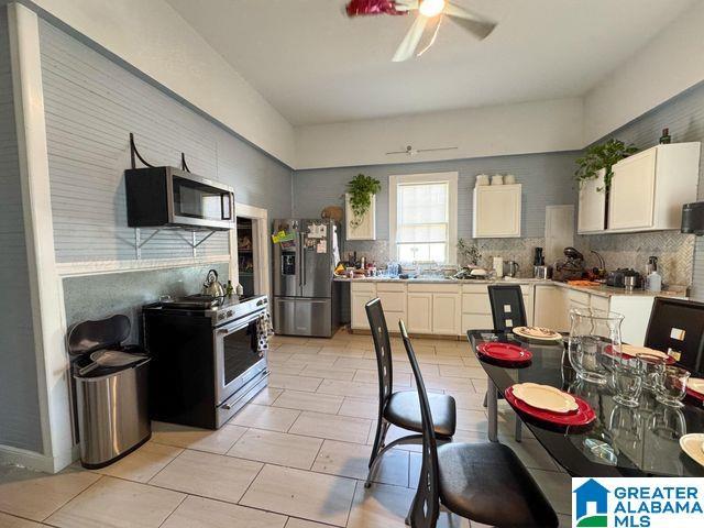 kitchen with decorative backsplash, appliances with stainless steel finishes, light countertops, white cabinets, and a ceiling fan