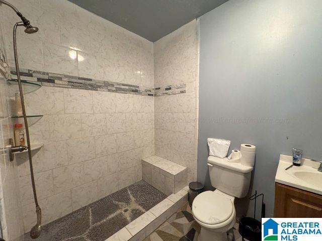 bathroom with toilet, vanity, and tiled shower