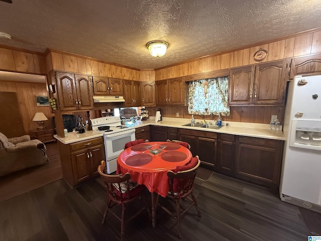 kitchen with wood walls, white appliances, a textured ceiling, and under cabinet range hood