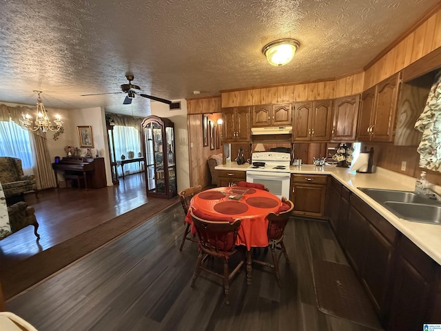 kitchen with a sink, light countertops, under cabinet range hood, wooden walls, and white range with electric cooktop
