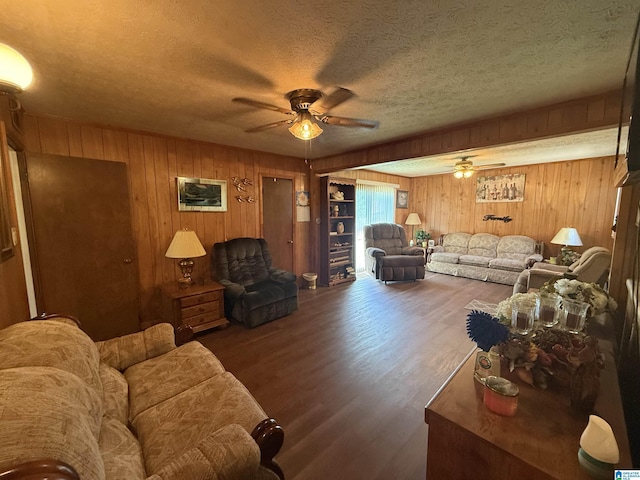 living room with wood finished floors, wooden walls, a ceiling fan, and a textured ceiling