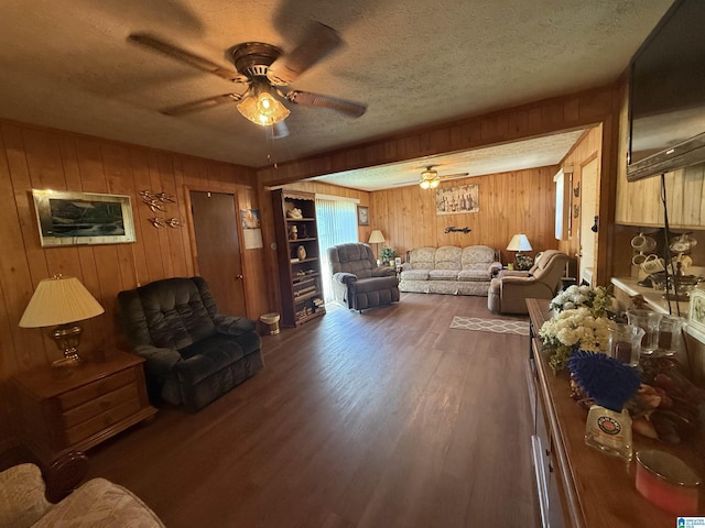 living area with a textured ceiling, ceiling fan, wood walls, and wood finished floors