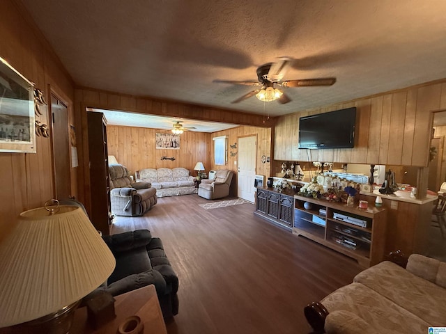 living area with wood finished floors, a ceiling fan, wooden walls, and a textured ceiling