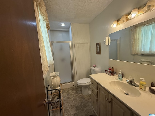 bathroom with toilet, a stall shower, a textured ceiling, and vanity