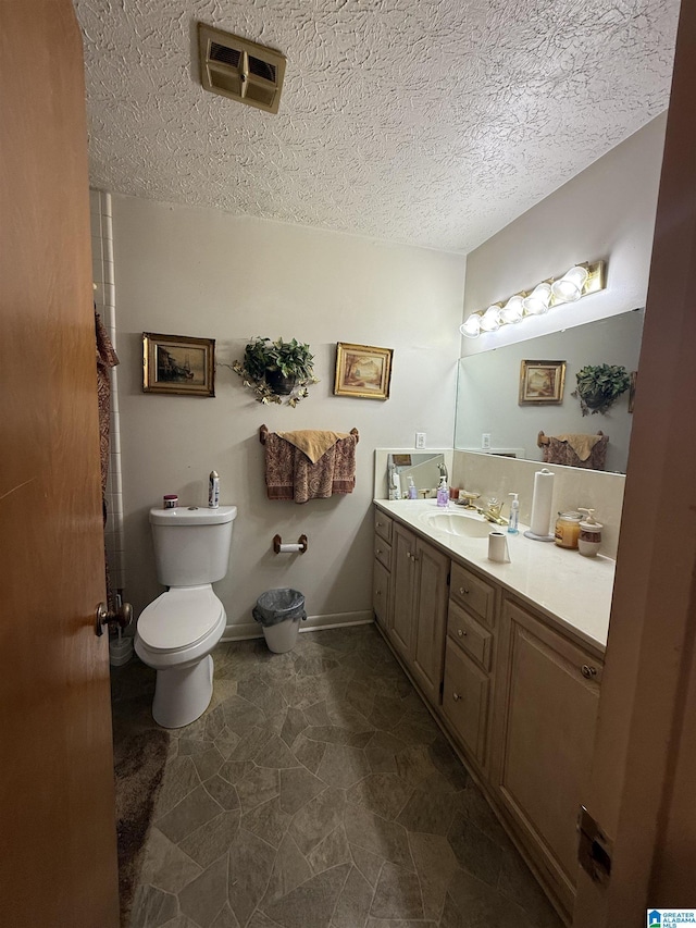 bathroom featuring toilet, a textured ceiling, visible vents, and vanity
