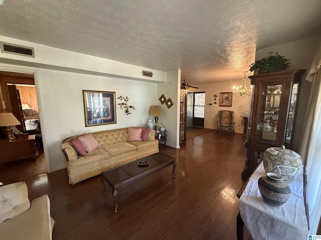 living room with a textured ceiling, visible vents, wood finished floors, and a notable chandelier