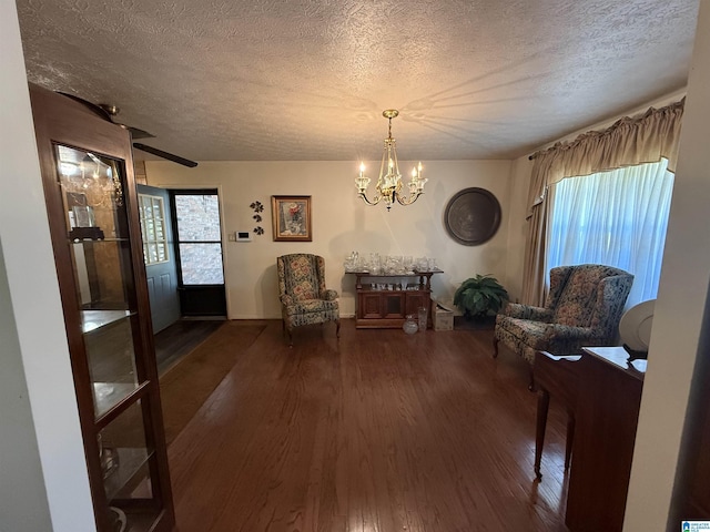 sitting room with a chandelier, baseboards, wood finished floors, and a textured ceiling