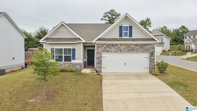craftsman-style house featuring driveway, roof with shingles, a front yard, and stone siding
