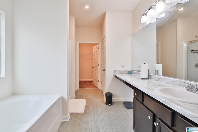 bathroom with recessed lighting, a bath, baseboards, a spacious closet, and a stall shower