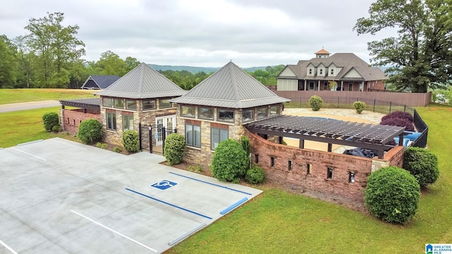 exterior space with metal roof, a lawn, stone siding, and fence