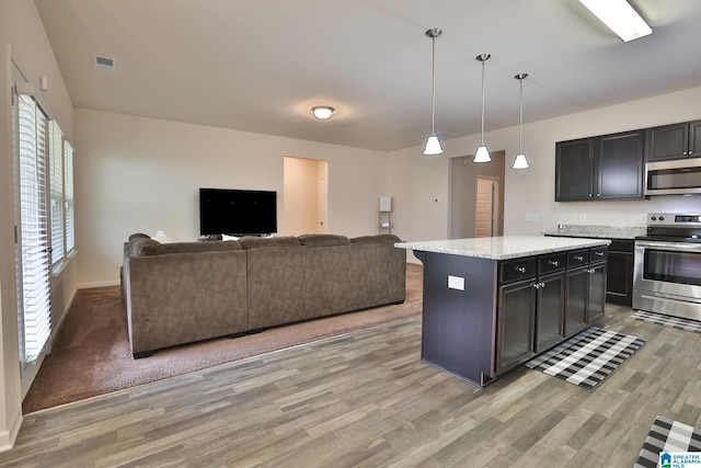 kitchen with open floor plan, visible vents, stainless steel appliances, and light wood finished floors