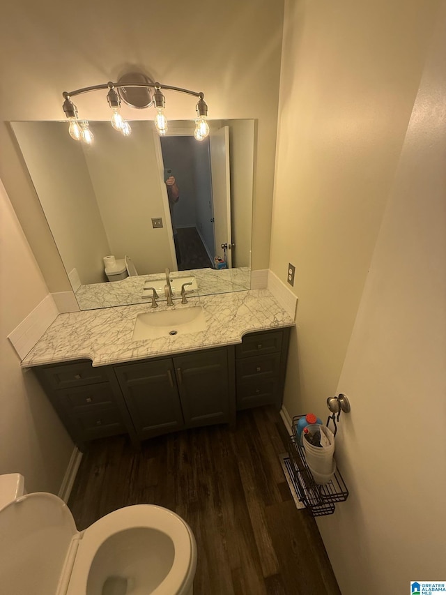 half bathroom featuring toilet, vanity, and wood finished floors