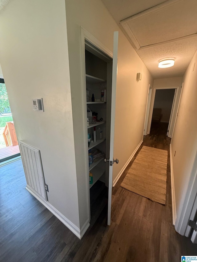 hallway with attic access, baseboards, and dark wood finished floors